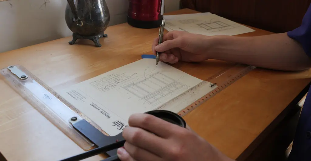 Person measuring and sketching custom gun safe dimensions on paper, with drafting tools and notes, emphasizing the importance of precise measurements for firearm collection.
