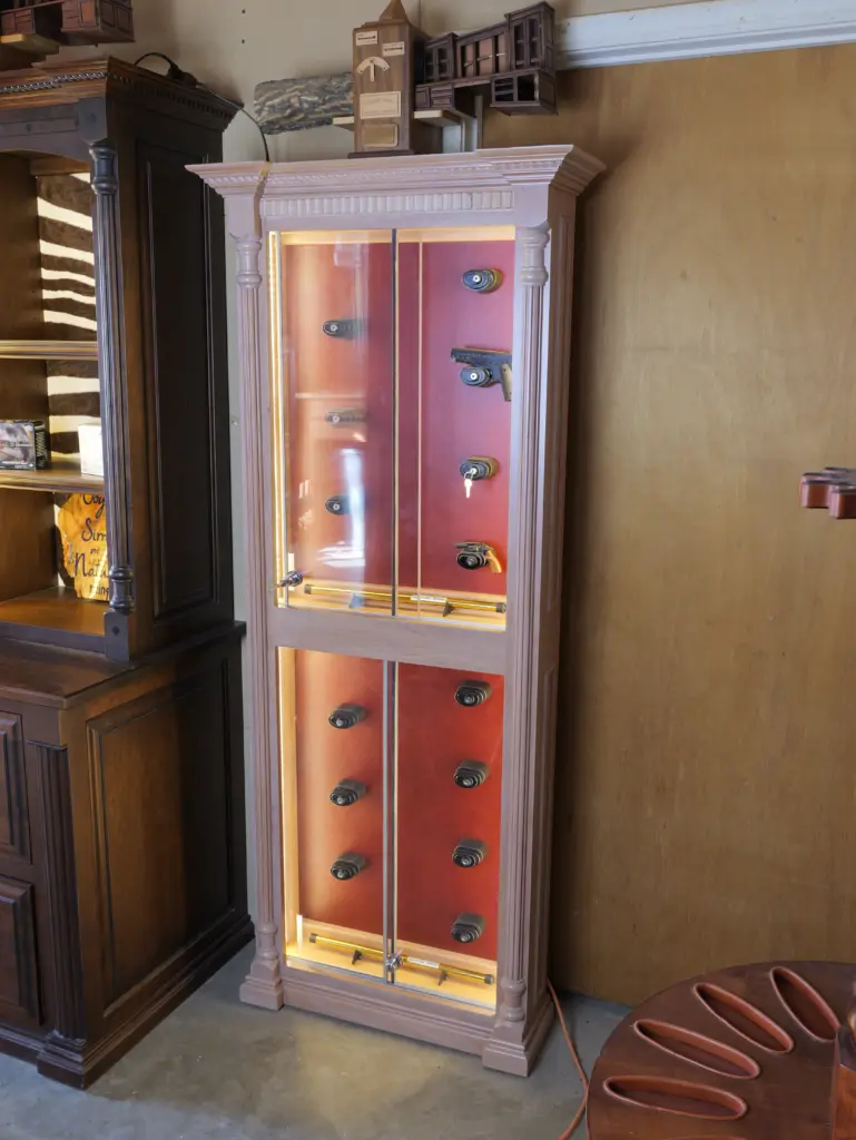 Gun display safe with illuminated interior, showcasing firearms and accessories, highlighting LED lighting features for visibility and aesthetics.